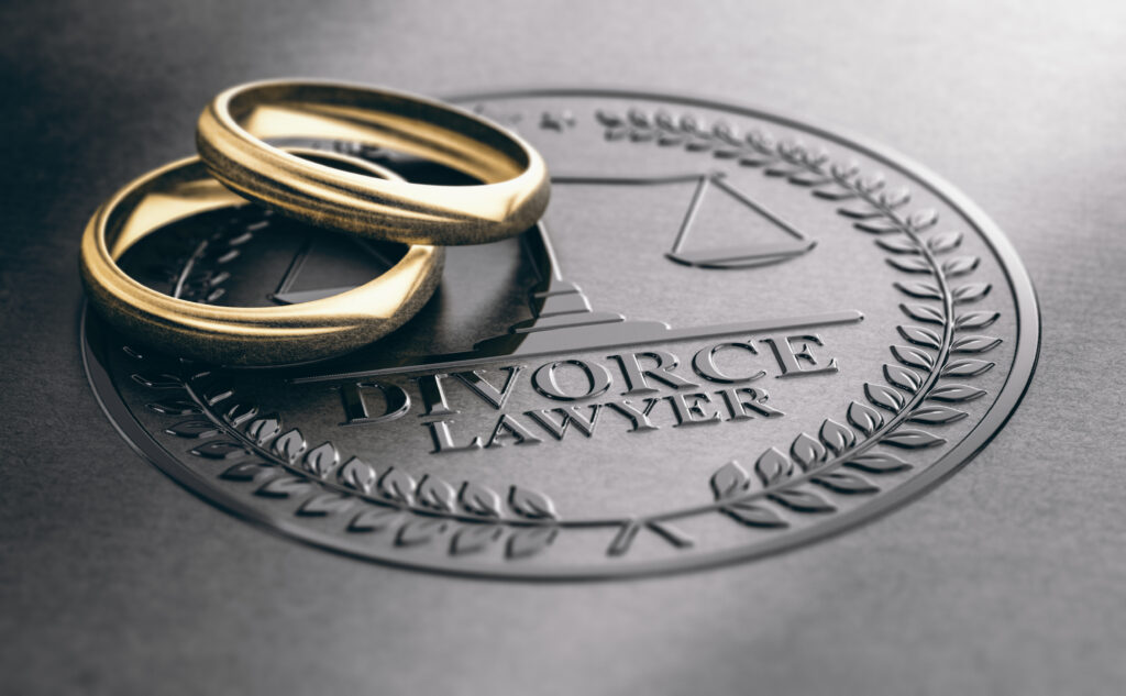 2 plain gold wedding bands lying on an embossed seal with the word Divorce Lawyer and legal scales.